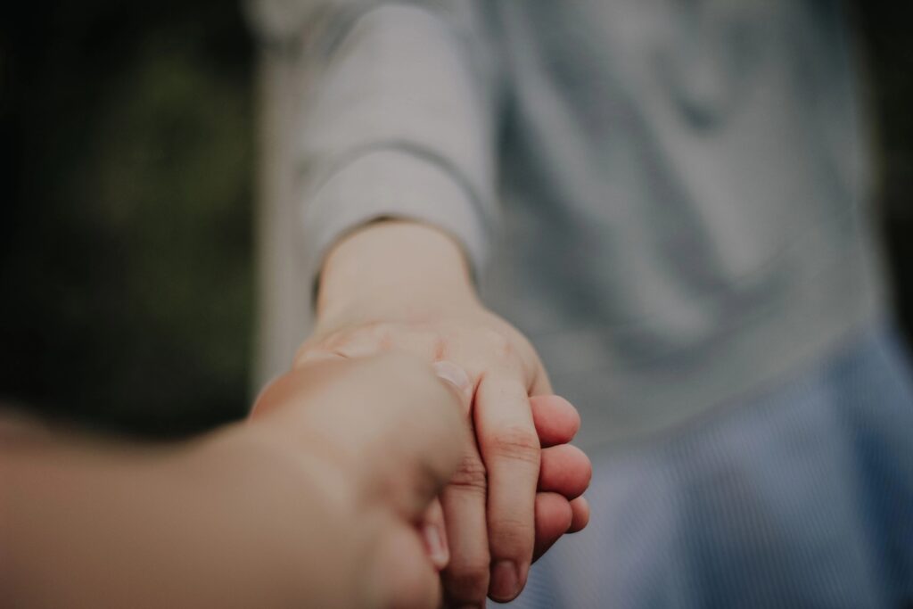 Nahaufnahme: Eine Hand hält die Hand einer anderen Person.