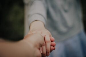 Nahaufnahme: Eine Hand hält die Hand einer anderen Person.